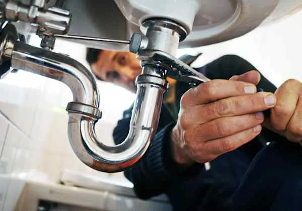 Plumber repairing sink pipes — home plumbing repair service