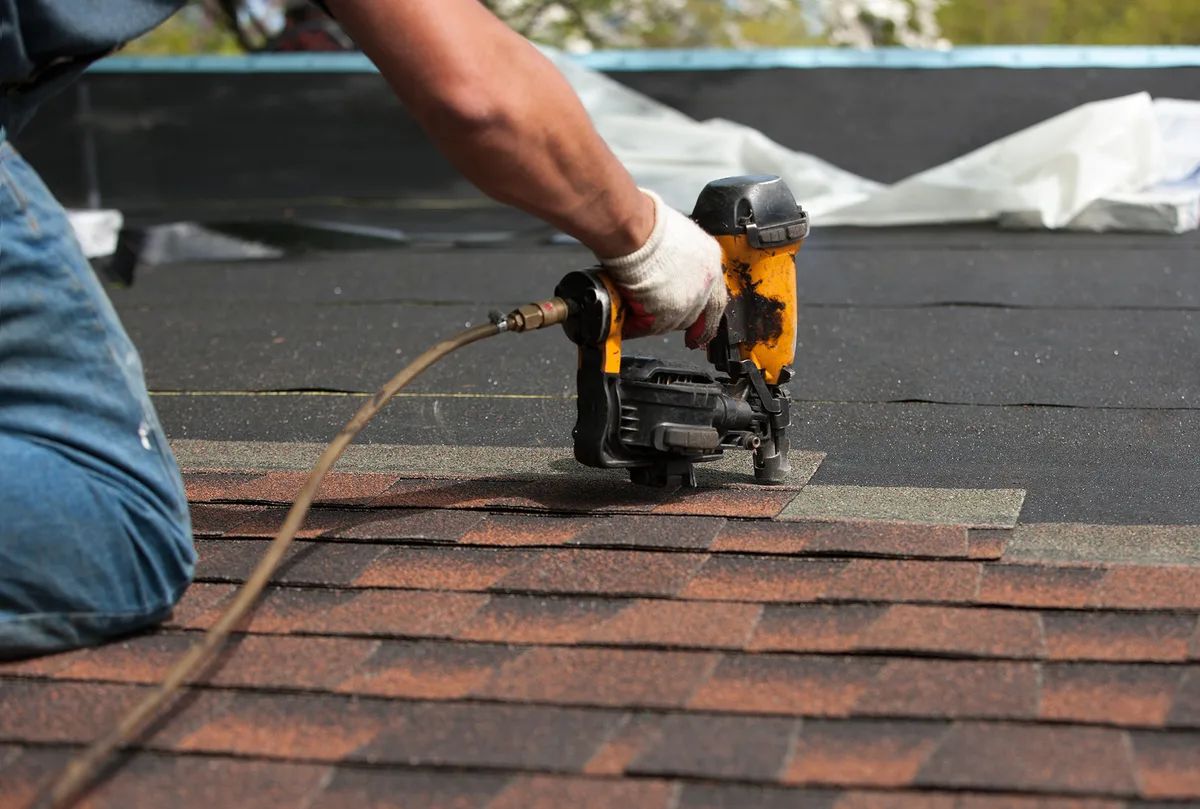 Roofer nailing shingles — roof repair service in Massachusetts